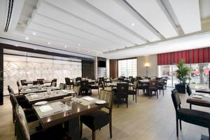 Innenansicht des Restaurants im Khalidiya Palace Rayhaan by Rotana mit eingerichteten Tischen und Stühlen.