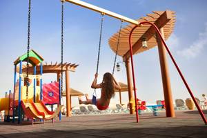 Mädchen auf einer Schaukel im Kinderspielplatz des Khalidiya Palace Rayhaan by Rotana