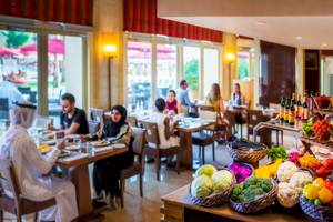 Gäste, die im Innenrestaurant des Khalidiya Palace Rayhaan by Rotana sitzen und essen.