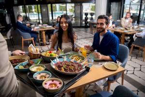 Paar sitzt an einem Tisch im Khalidiya Palace Rayhaan by Rotana und genießt eine Mahlzeit mit verschiedenen Gerichten.