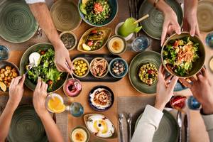 Mehrere Personen essen Salat an einem Tisch im Hotel Khalidiya Palace Rayhaan by Rotana.