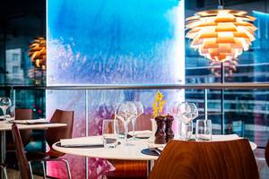 Innenansicht des Restaurants im Park Plaza County Hall London mit Tisch, Gläsern und blauer Wand
