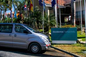 Silberner Van vor dem Occidental Tamarindo Hotel mit vielen Flaggen im Hintergrund.