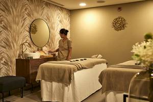 Spa-Behandlung im Riu Dubai mit einer Frau, die einen Massagetisch vorbereitet.