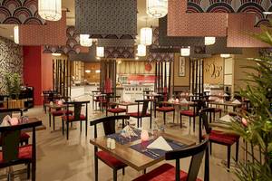 Innenraum des Riu Dubai Hotel Restaurants mit roten Stühlen und Tischdecken.