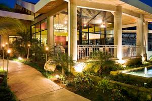 Abendliche Ansicht des Hotels Occidental Tamarindo mit beleuchtetem Gehweg und Terrasse.