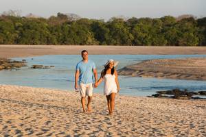 Ein Paar spaziert Hand in Hand am Strand vor dem Occidental Tamarindo Hotel.