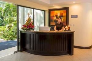 Rezeptionistin des Occidental Tamarindo Hotels lächelt vor einem großen Gemälde.