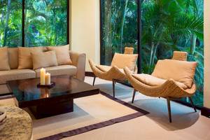 Wohnzimmer im Occidental Tamarindo Hotel mit Couch, Kerzen und Fenstern.