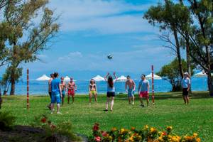 Gruppe spielt Volleyball im Freibad mit Blick auf den Ozean und Palmen