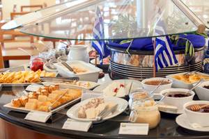 Frühstücksbuffet im Louis Kerkyra Blue Hotel mit verschiedenen Gerichten und Flaggen Griechenlands.
