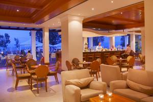 Loungebereich des Louis Kerkyra Blue Hotels mit Bar, Tischen und Stühlen sowie Ausblick auf den Garten.