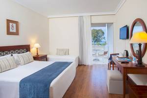 Innenansicht eines Hotelzimmers des Louis Kerkyra Blue mit zwei Betten, Schreibtisch, Lampen und Fernseher.