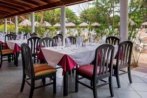Restaurantbereich im Occidental Tamarindo Hotel mit Tisch und Stühlen, serviert für Mahlzeiten.