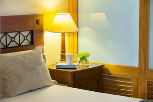 Bett im Zimmer im Louis Kerkyra Blue Hotel mit Kissen, Nachttisch und Lampe.