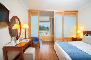 Innenansicht des Louis Kerkyra Blue Hotelzimmers mit Bett, Schreibtisch und Balkonzugang