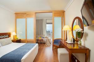 Innenansicht eines Hotelzimmers im Louis Kerkyra Blue mit Bett, Schreibtisch und Balkonzugang.