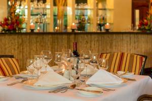 Ein gedeckter Tisch im Occidental Tamarindo Hotel mit Flasche, Gläsern und Besteck.