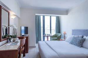 Innenansicht eines Zimmers im Mitsis La Vita Beach Hotel mit Bett, Schreibtisch und Balkon.