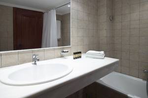 Badezimmer im Mitsis La Vita Beach Hotel mit Spiegel, Waschbecken und Badewanne.