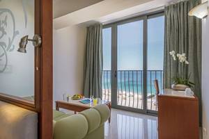 Innenansicht eines Zimmers im Mitsis La Vita Beach Hotel mit Blick auf einen Balkon und das Meer.