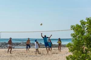 Gruppe von Spielern, die Volleyball auf dem Strand vor dem Occidental Tamarindo Hotel spielen.