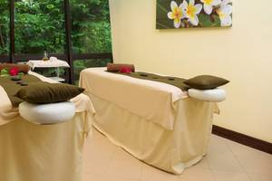 Massage-Behandlungsraum im Hotel Occidental Tamarindo mit Blick auf die Natur, zwei Massageliegen mit Kissen und Steinen.