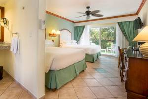 Hotelzimmer im Occidental Tamarindo mit zwei Betten, Badezimmerspiegel und Fenstern.