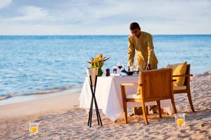 Ein Kellner bereitet ein Essen auf dem Strand am Dhawa Ihuru Hotel vor.