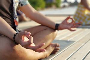 Eine Person praktiziert Yoga und Meditation am Strand des Dhawa Ihuru Hotels.