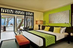 Schlafzimmer im Dhawa Ihuru Hotel mit grünen Wänden, einem großen Bett, und einer Terrasse mit Blick auf den Ozean.