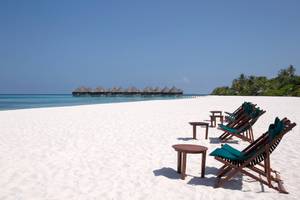 Coco Palm Dhuni Kolhu Strand mit weißen Liegestühlen und kleinen Tischen