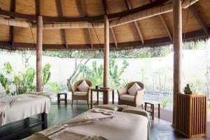 Massageraum im Coco Palm Dhuni Kolhu Hotel mit zwei Liegen und Sitzmöbeln.