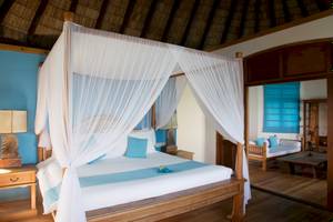 Ein Schlafzimmer im Coco Palm Dhuni Kolhu Hotel mit einem Bett unter einem Baldachin.