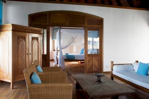 Innenansicht des Coco Palm Dhuni Kolhu Hotels mit Wohnzimmer und Schlafzimmerbereich.
