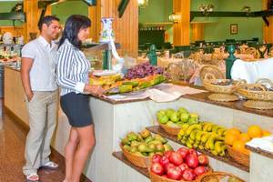 Ein Paar im Bluesea Costa Bastian Hotel Restaurant, das ein Buffet betrachtet.