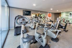 Fitnessbereich im Barcelo Santiago Hotel mit modernen Trainingsgeräten und einer großen Wandgrafik.