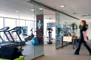 Fitnesscenter im Barcelo Santiago Hotel mit Laufbändern, Trainingsgeräten und einer Person, die vorbeigeht.