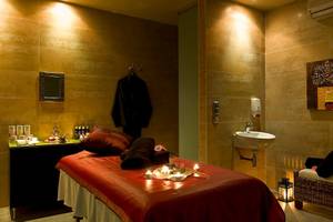 Spa-Behandlungsraum im Barcelo Santiago Hotel mit Bett, Kerzen und Handtüchern.