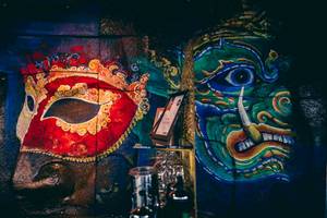 Wandmalereien im Siam@Siam Design Hotel Bangkok zeigen bunte Masken und mythische Gesichter.