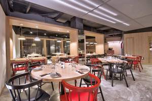 Innenbereich des Restaurants im Doubletree by Hilton Malta mit runden Tischen und Stühlen.