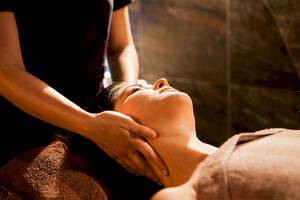 Massage im Doubletree by Hilton Malta, eine Frau genießt eine Gesichtsmassage.