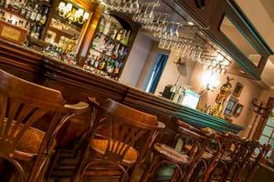 Innenansicht der Bar im AX The Victoria Hotel mit Holzstühlen und Tresen.