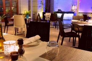Ein Restauranttisch im AX The Victoria Hotel mit Kerzen, Flaschen und Geschirr.
