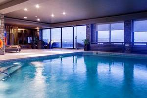 Innenpool im AX The Victoria Hotel mit großen Fenstern und Ausblick auf die Stadt.
