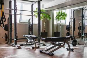 Fitnesscenter im AX The Victoria Hotel mit verschiedenen Trainingsgeräten und großen Fenstern.