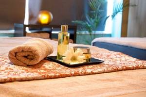 Spa-Behandlungsbereich im AX The Victoria Hotel mit einem Bett, Handtüchern, Blumen und Pflegeprodukten.