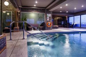Poolbereich im AX The Victoria Hotel mit Glaswänden und Inneneinrichtung.
