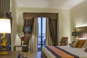 Zimmer im AX The Victoria Hotel mit Bett, Lampen und Balkon.