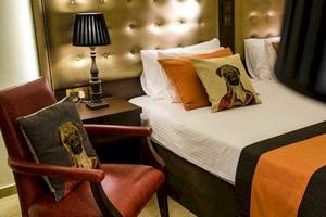 Hotelzimmer im AX The Victoria mit Bett, Kissen, Nachttisch und Stuhl.